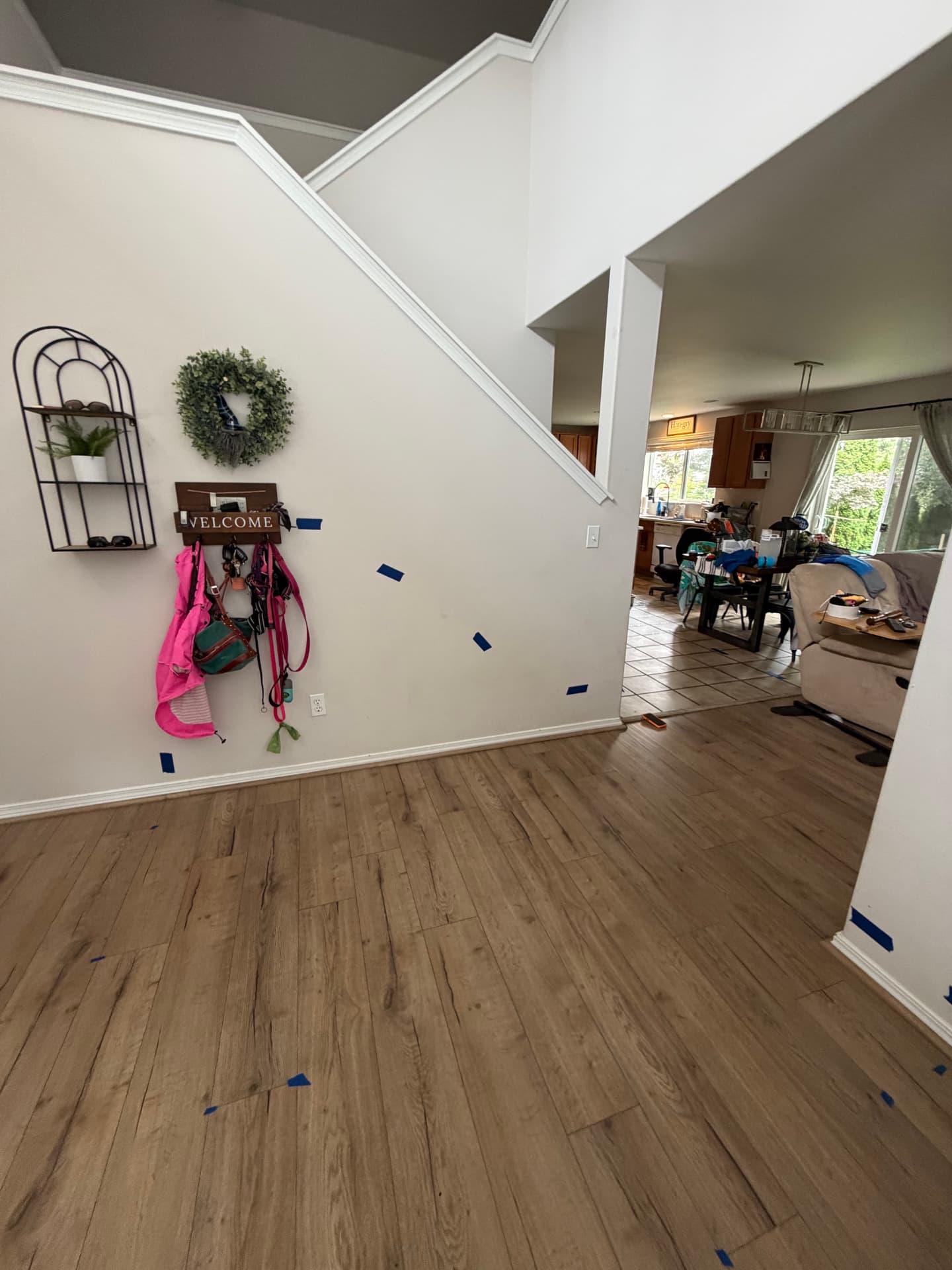 Blue tape marks on walls and wood flooring mapping moisture migration through a living room and hallway